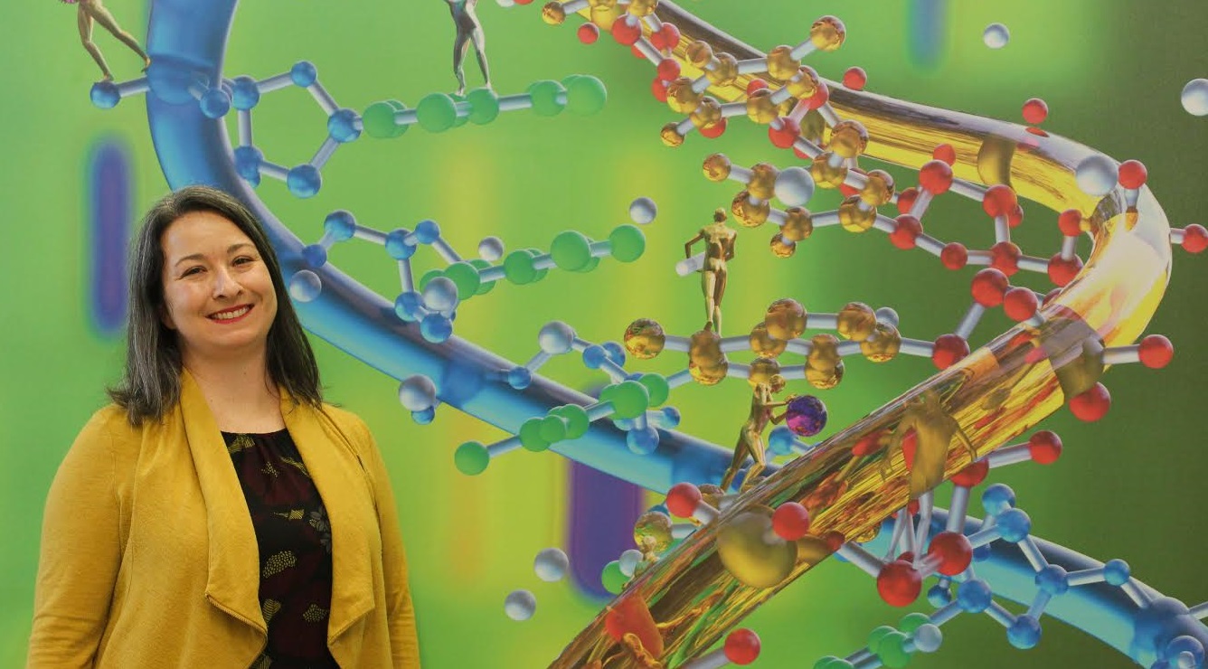 Jen standing in front of an artistic rendering of DNA.